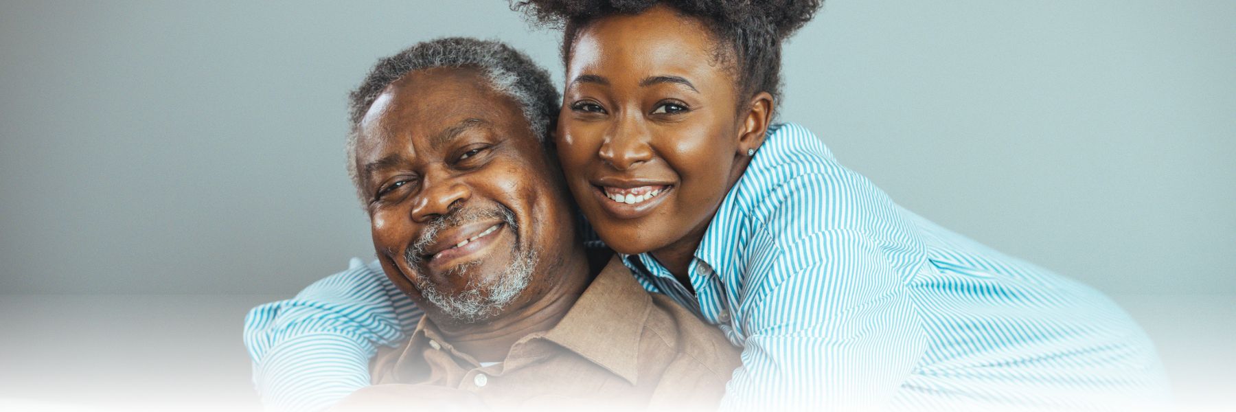 a senior adult aAfrican American man being hugged by his daughter