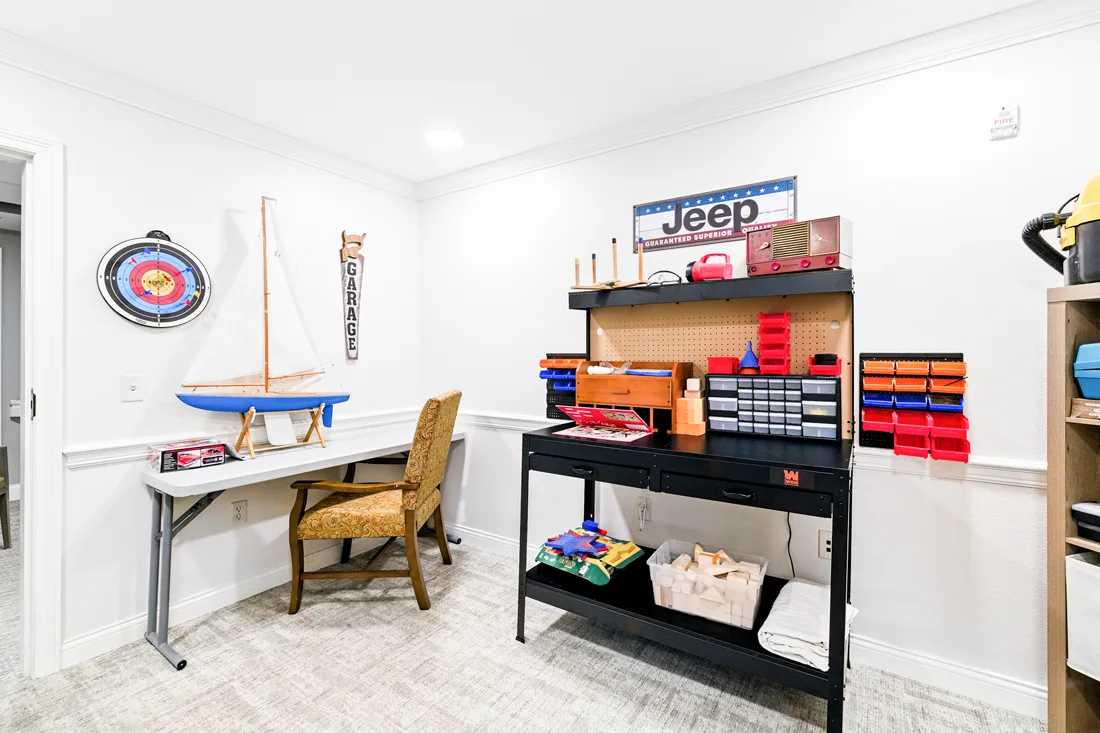 Common room with tools, supplies, and a desk and chair with a model sailboat