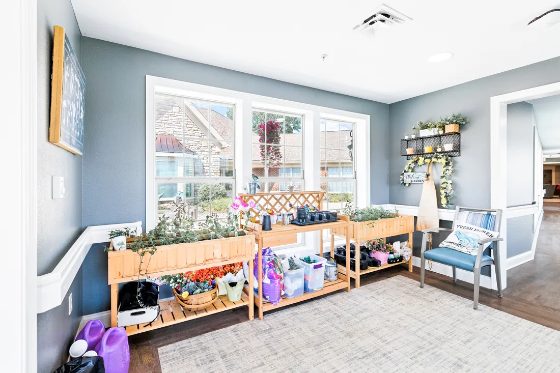Memory support common room with gardening supplies and potted plants and flowers