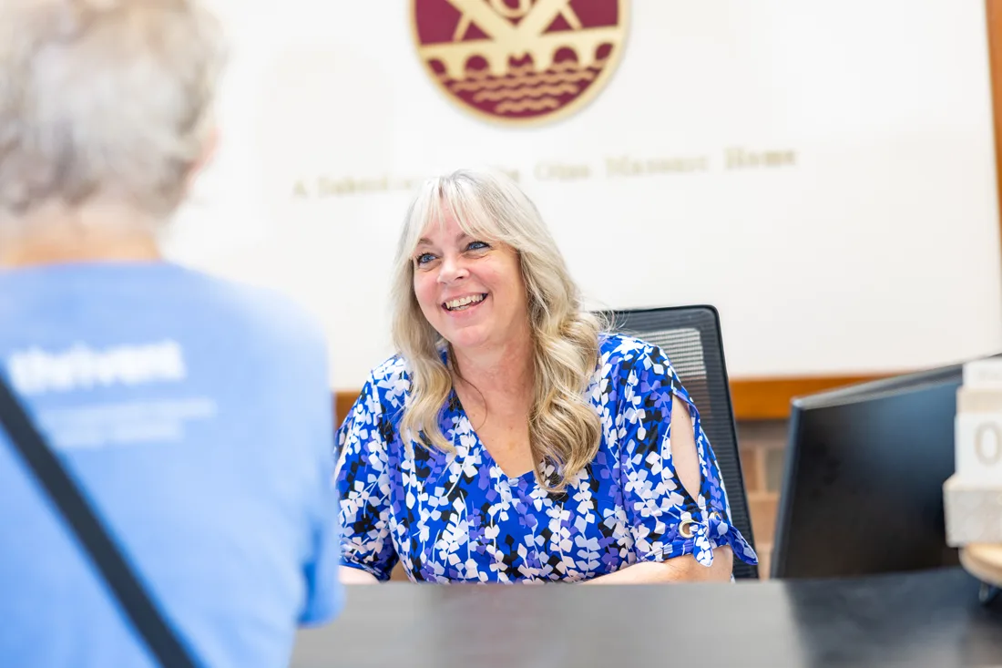 Staff member smiles and speaks with an older adult