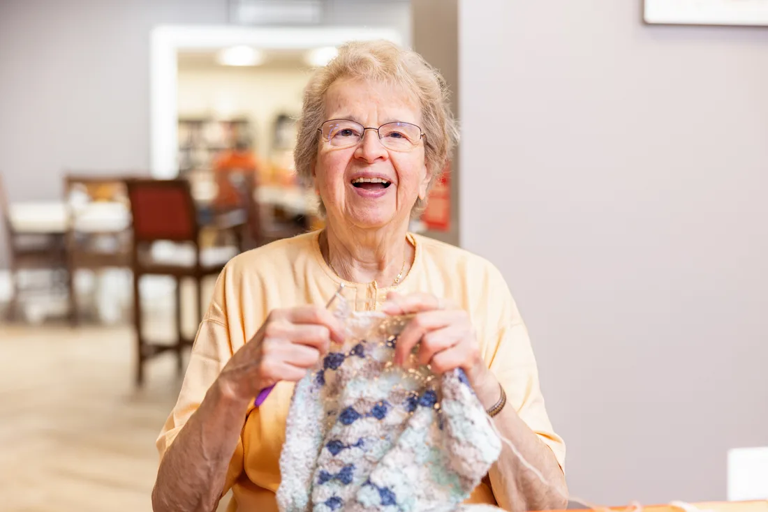 Older adult female knits or crochets with yarn