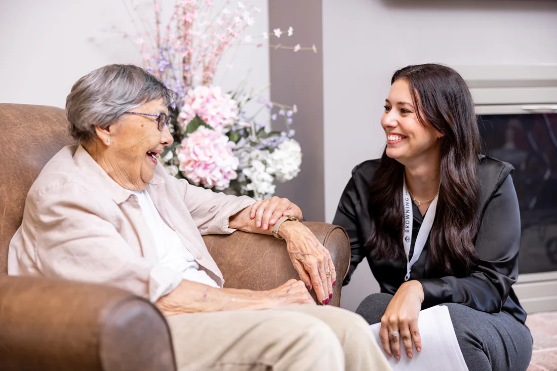 Older adult female sits and chats with a staff member