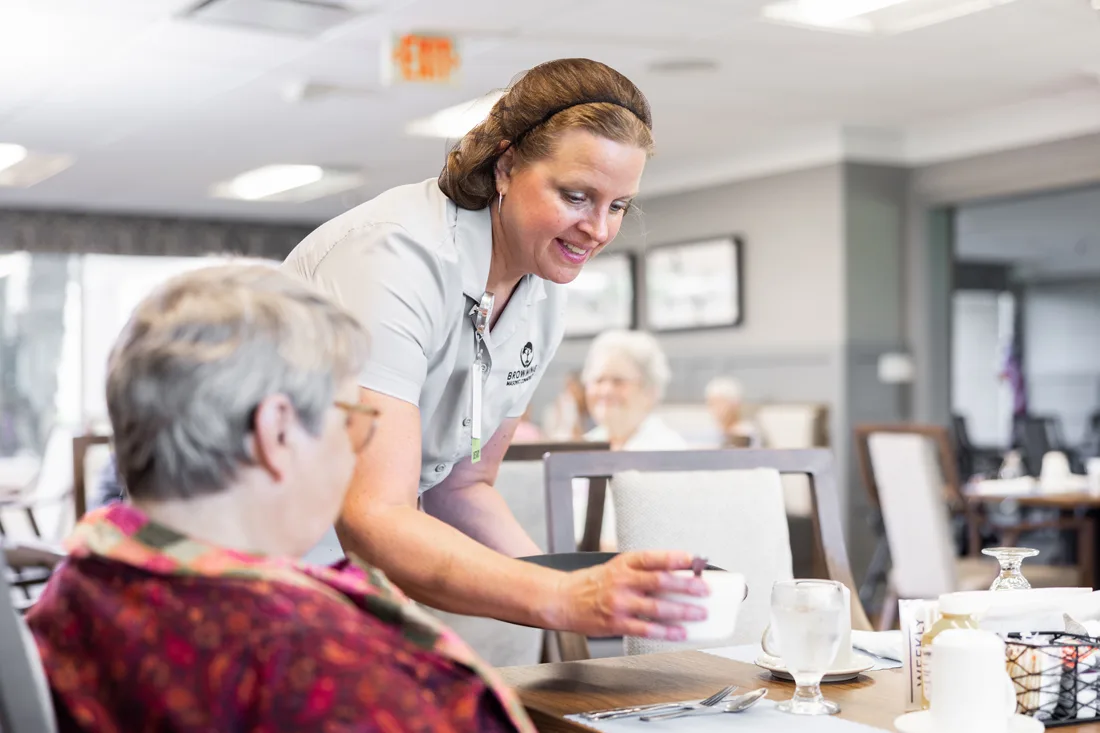 Staff member serves a resident food in the dining room
