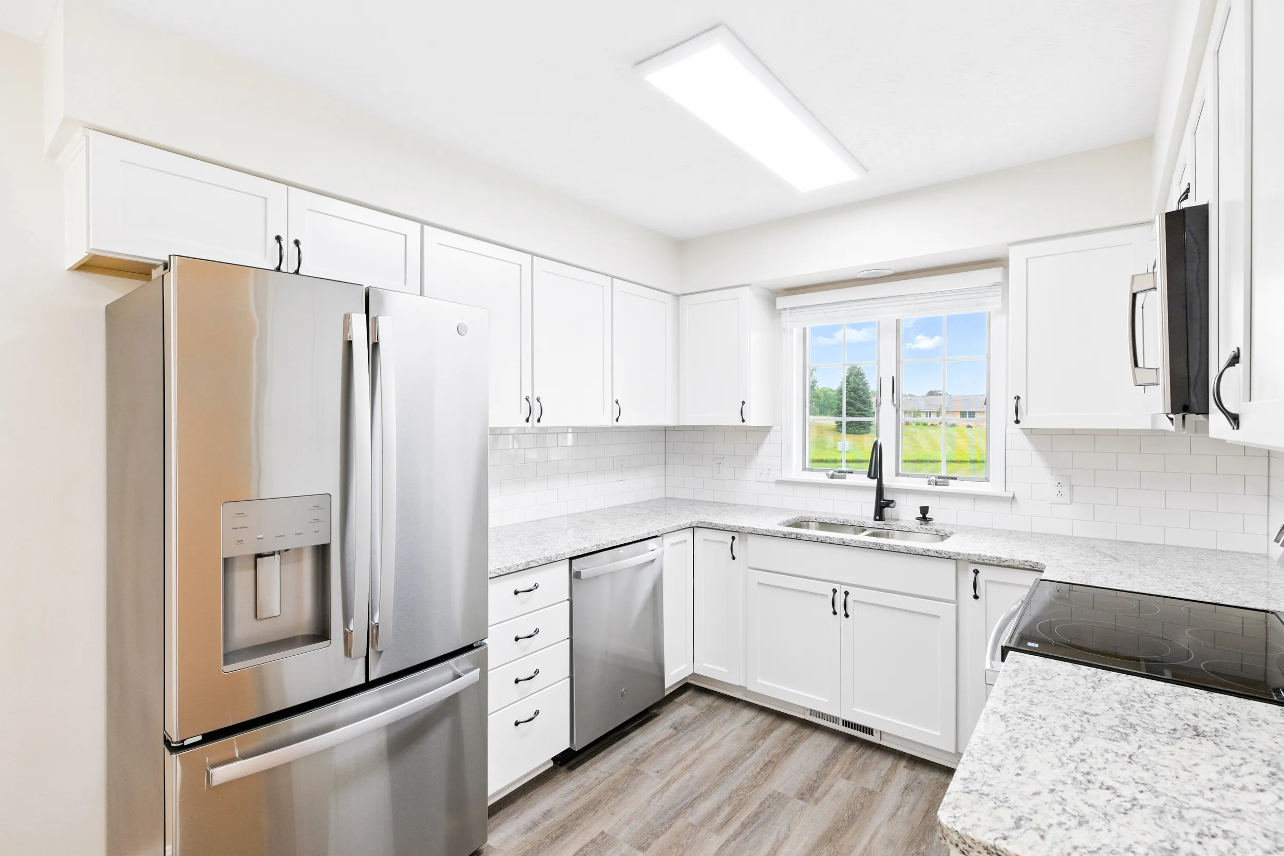 Kitchen with refrigerator, dishwasher, sink, window, cabinets, and a stove with a microwave