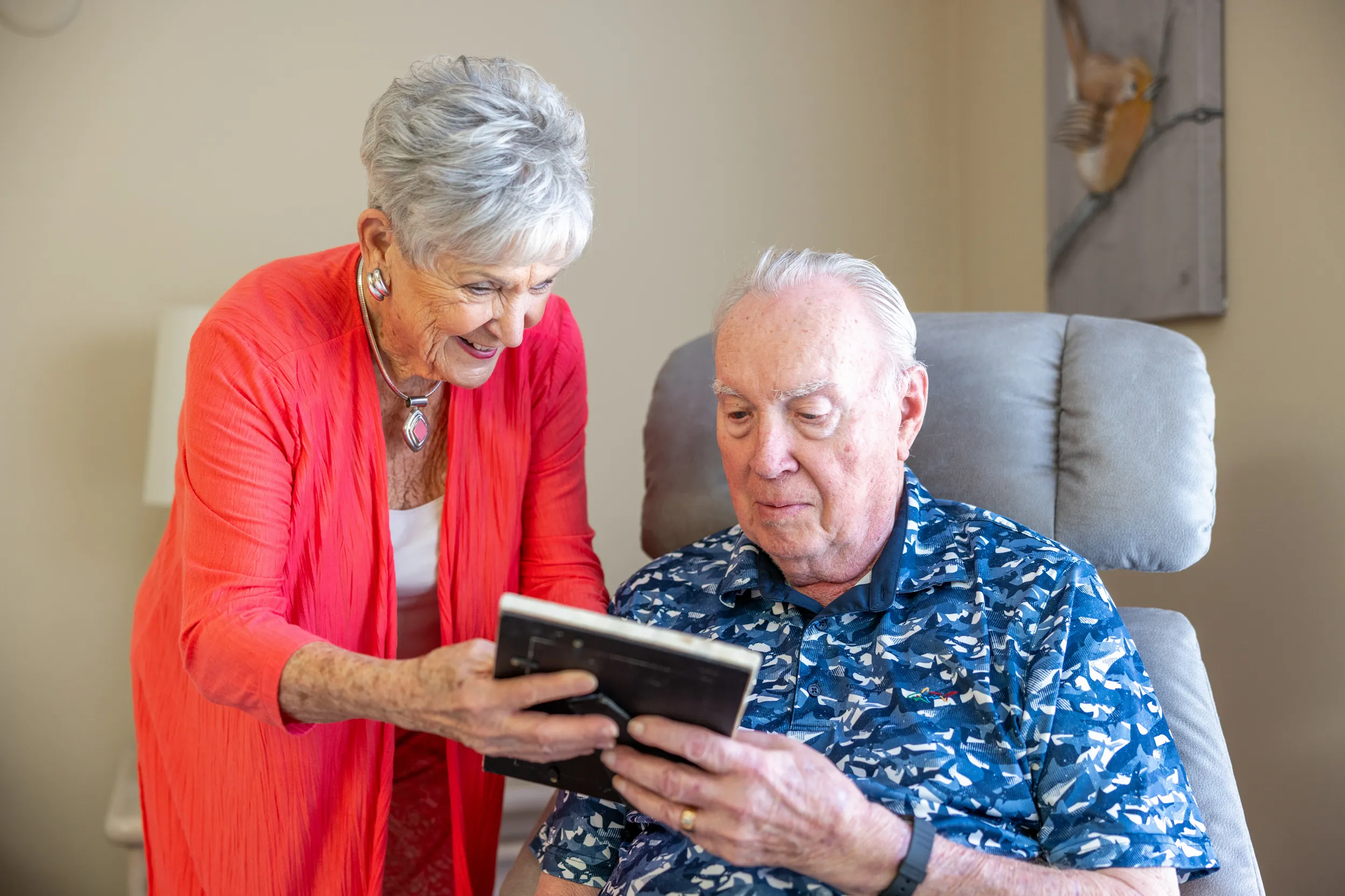 Older adult female and male look at a framed picture together