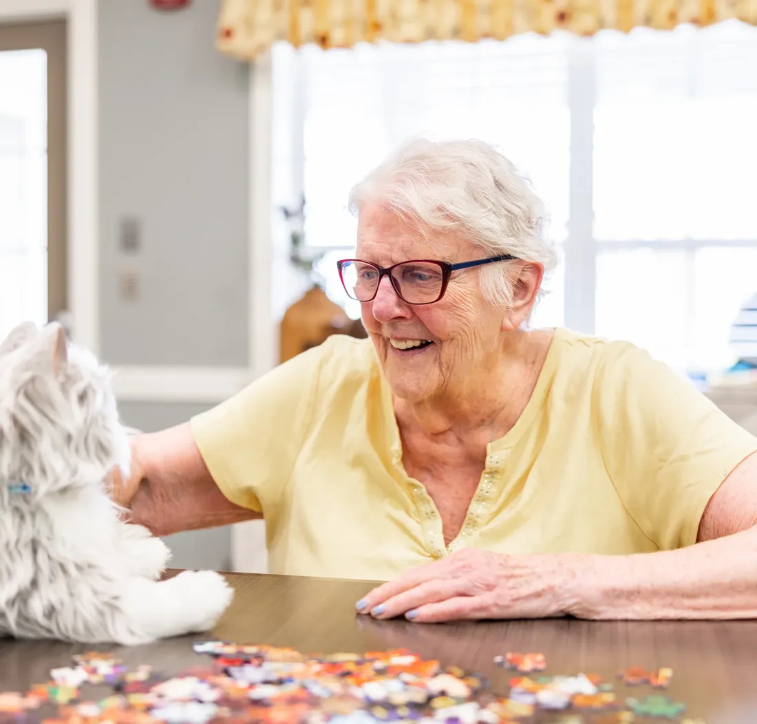 Older adult pets plush cat and works on a puzzle