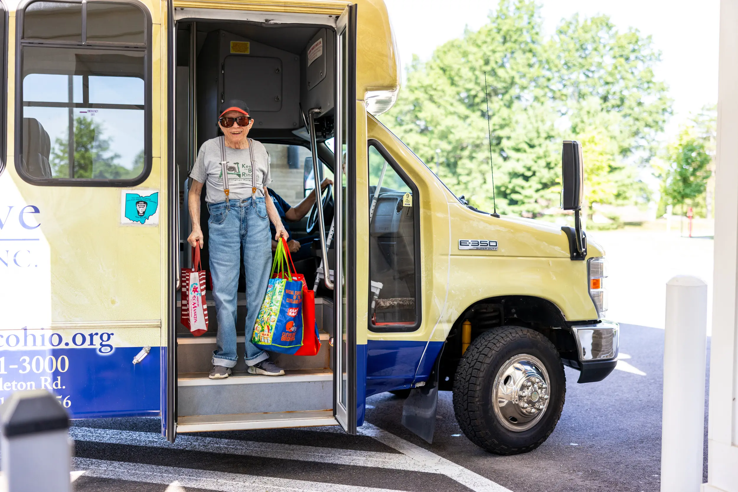 Older adult departing a bus carrying some reusable bags