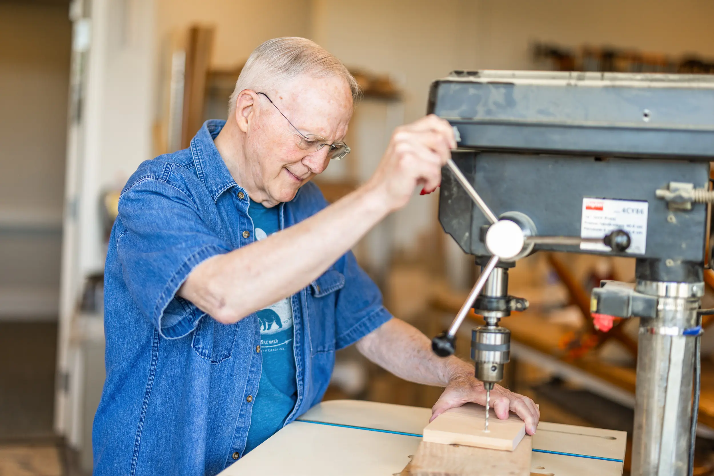 Older adult male uses equipment in a woodshop