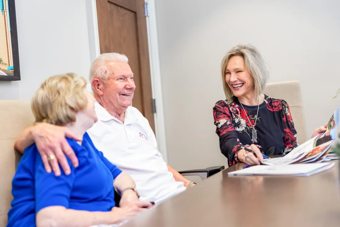 Staff member shows brochures to older adult couple