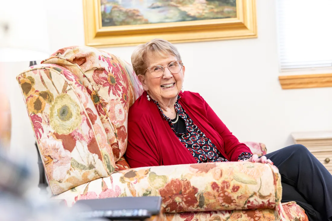 Older adult female sits on a chair smiling