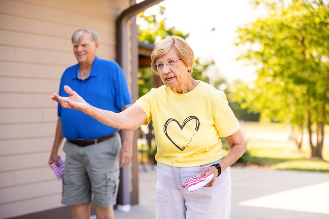 Older adult male and female play bean bag toss outdoors