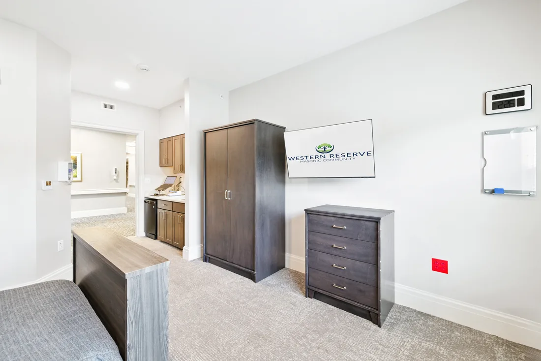 Suite with bed, dresser, and an area with a sink, refrigerator, cabinets, and a laptop