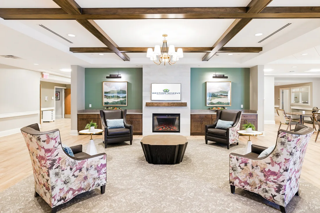 Living room with chairs and a fireplace with dining tables nearby