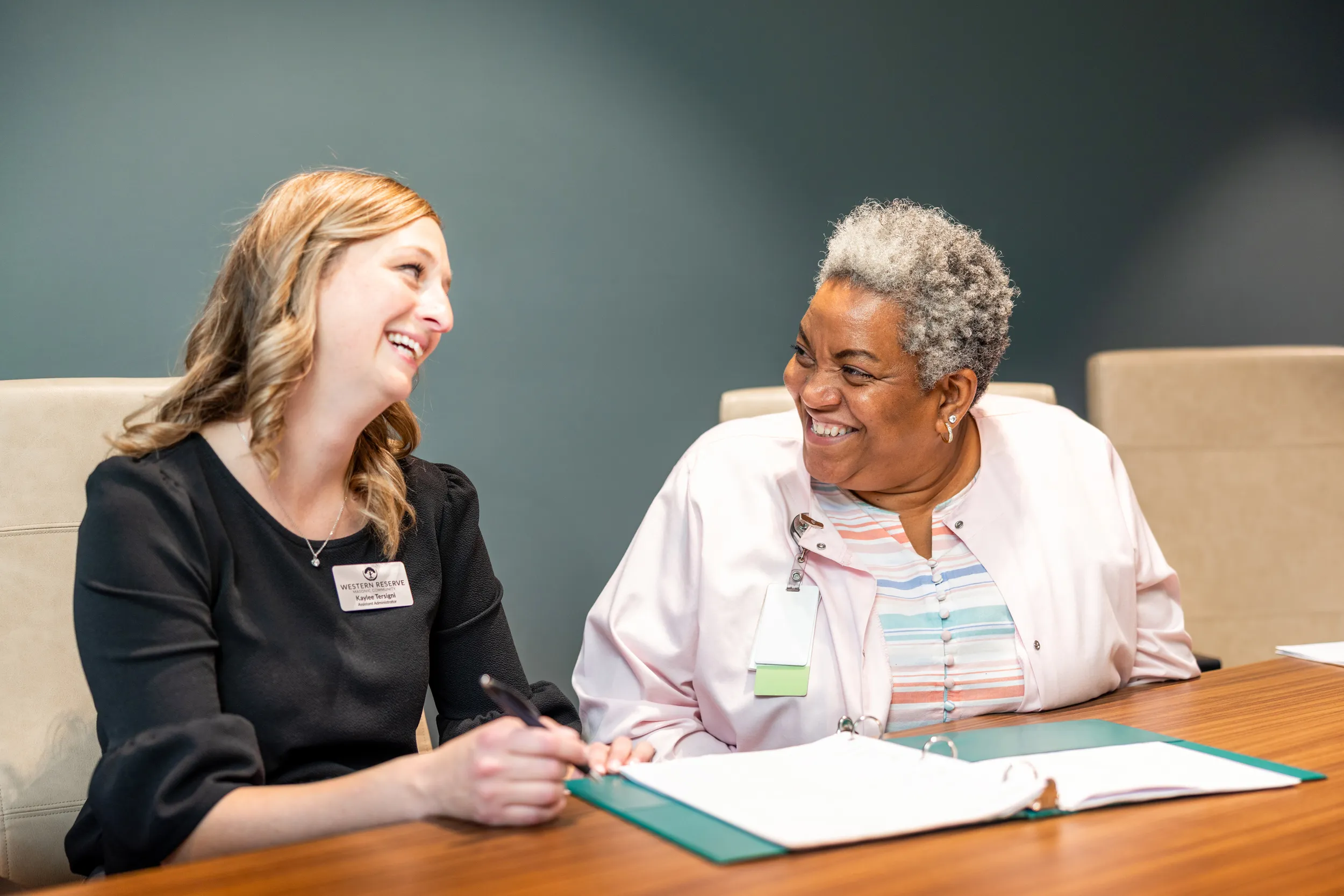 Staff members chatting and going over documents in a binder