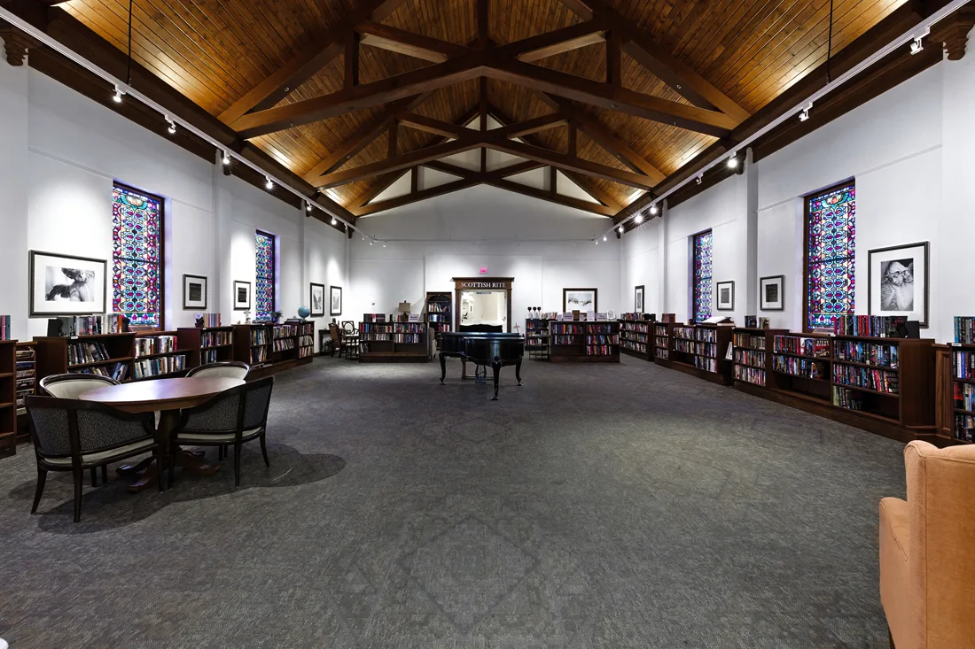 Grand piano in large room with walls lined with bookcases and books