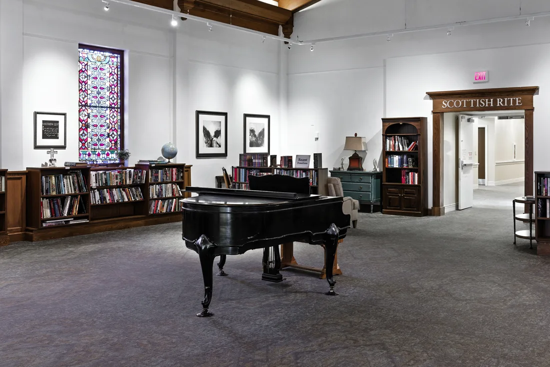 Grand piano in large room with walls lined with bookcases and books