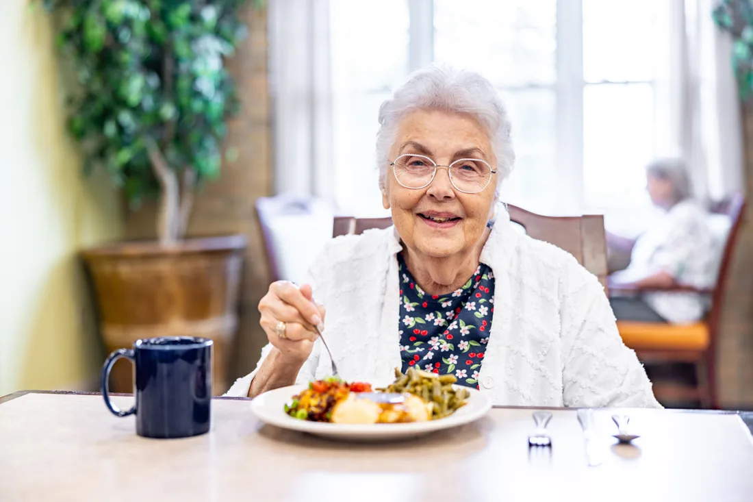 Older adult female eats a meal in the dining room