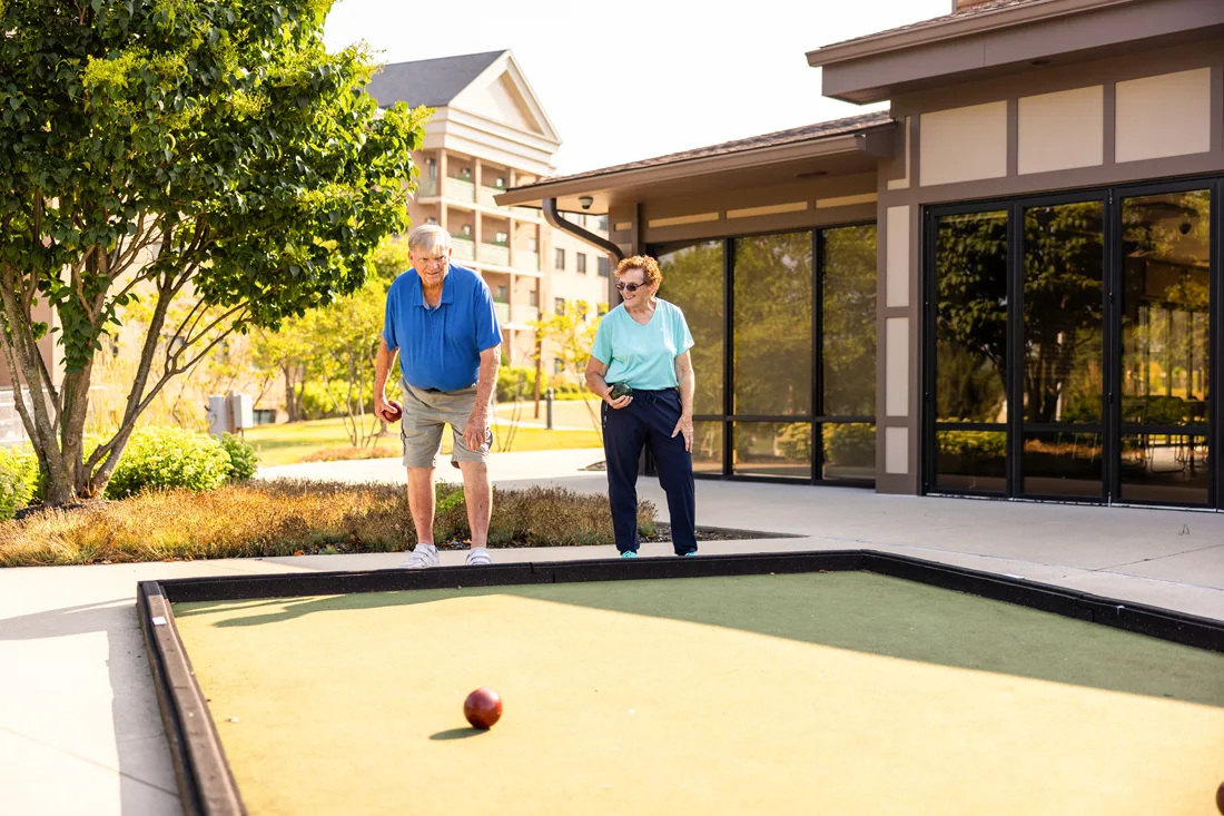 Older adult male and female play bocce ball outdoors
