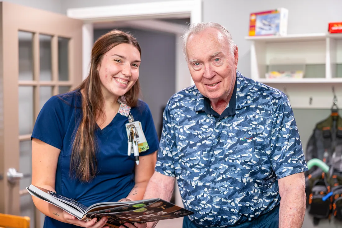 Staff member shows an older adult male pictures in a book