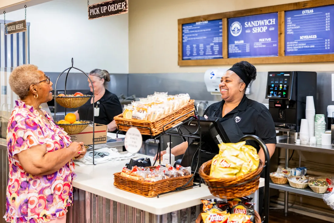Dining staff members take an order from a female resident in the sandwich shop