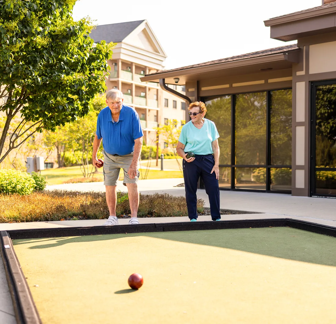 Older adult male and female play bocce ball outdoors