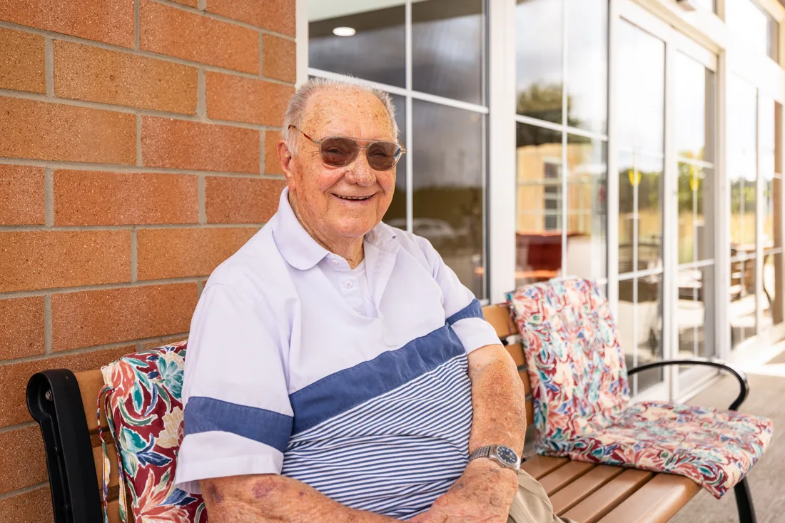 Older adult male sits outside on a bench