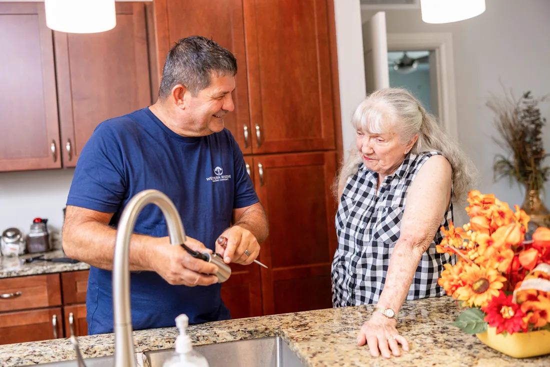 Male maintenance staff member fixes sink faucet for female resident