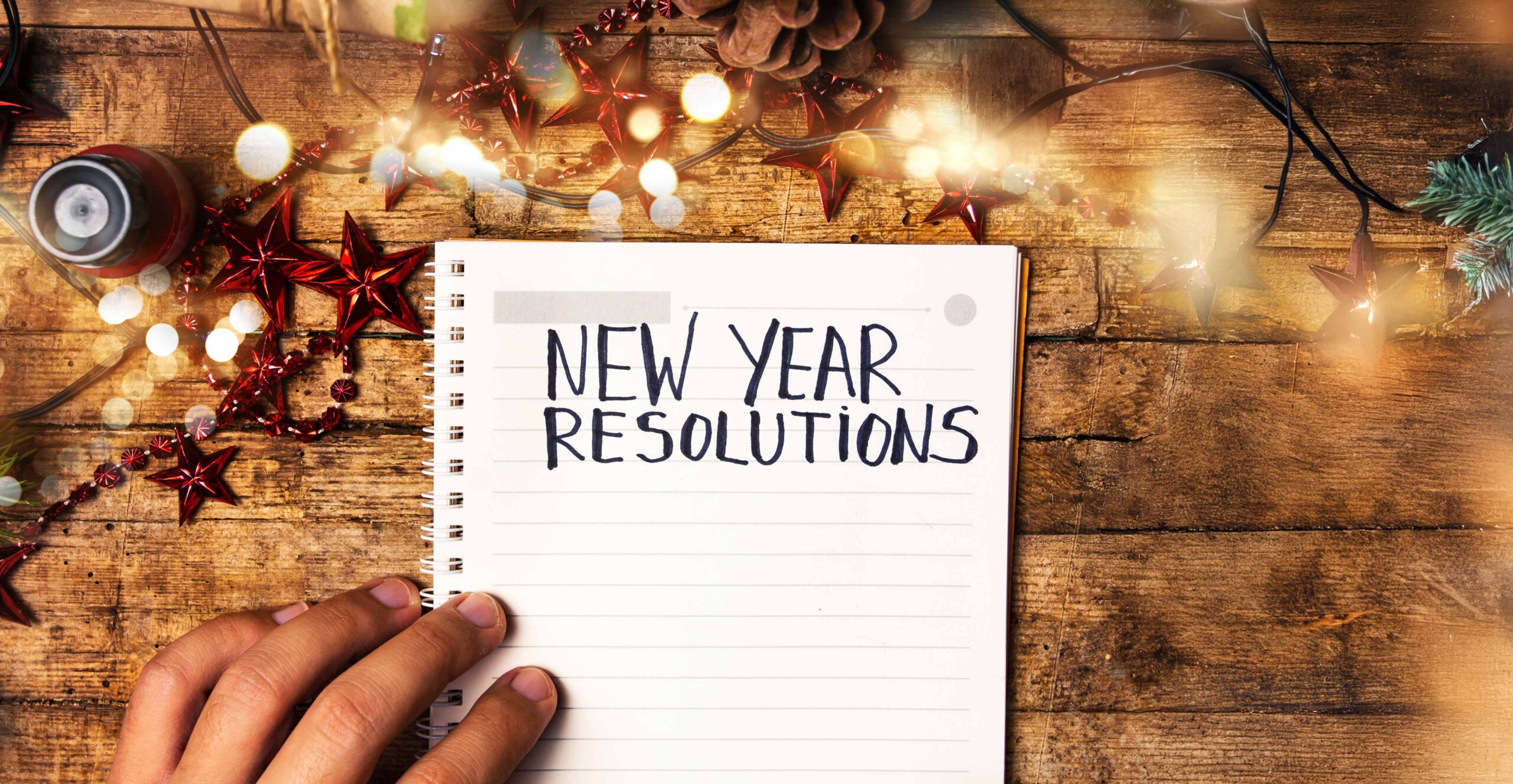 New Year Resolutions notebook near holiday lights