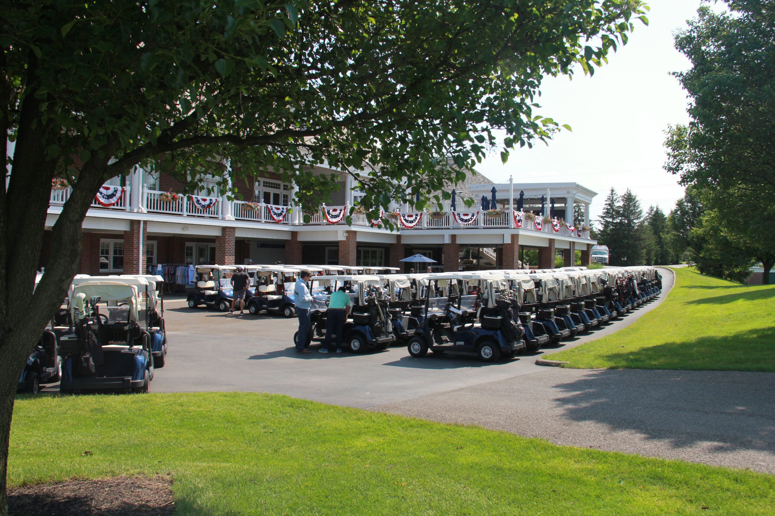 Multiple golf carts parked in several rows in front of a large building