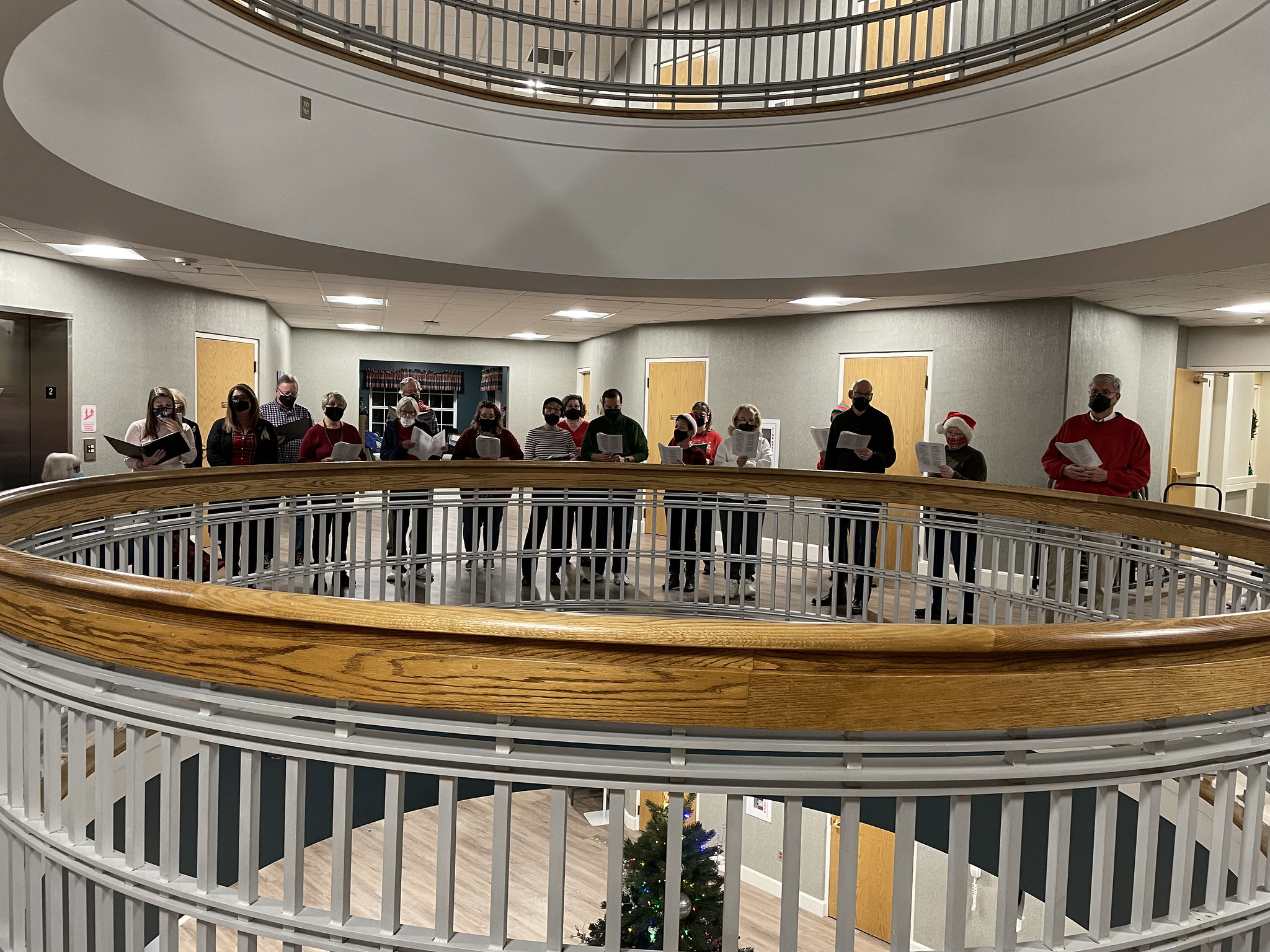 View of large group singing Christmas carols above the large, decorated Christmas tree