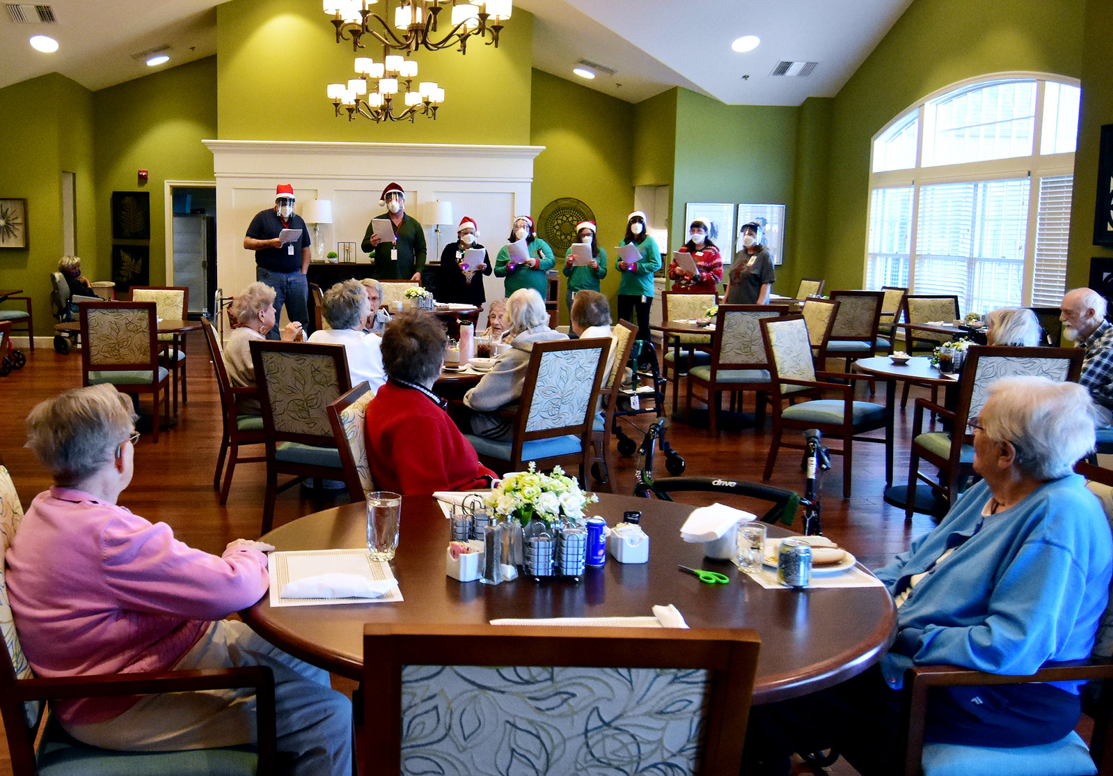 Staff members wearing eye protection and masks sing Christmas carols to residents