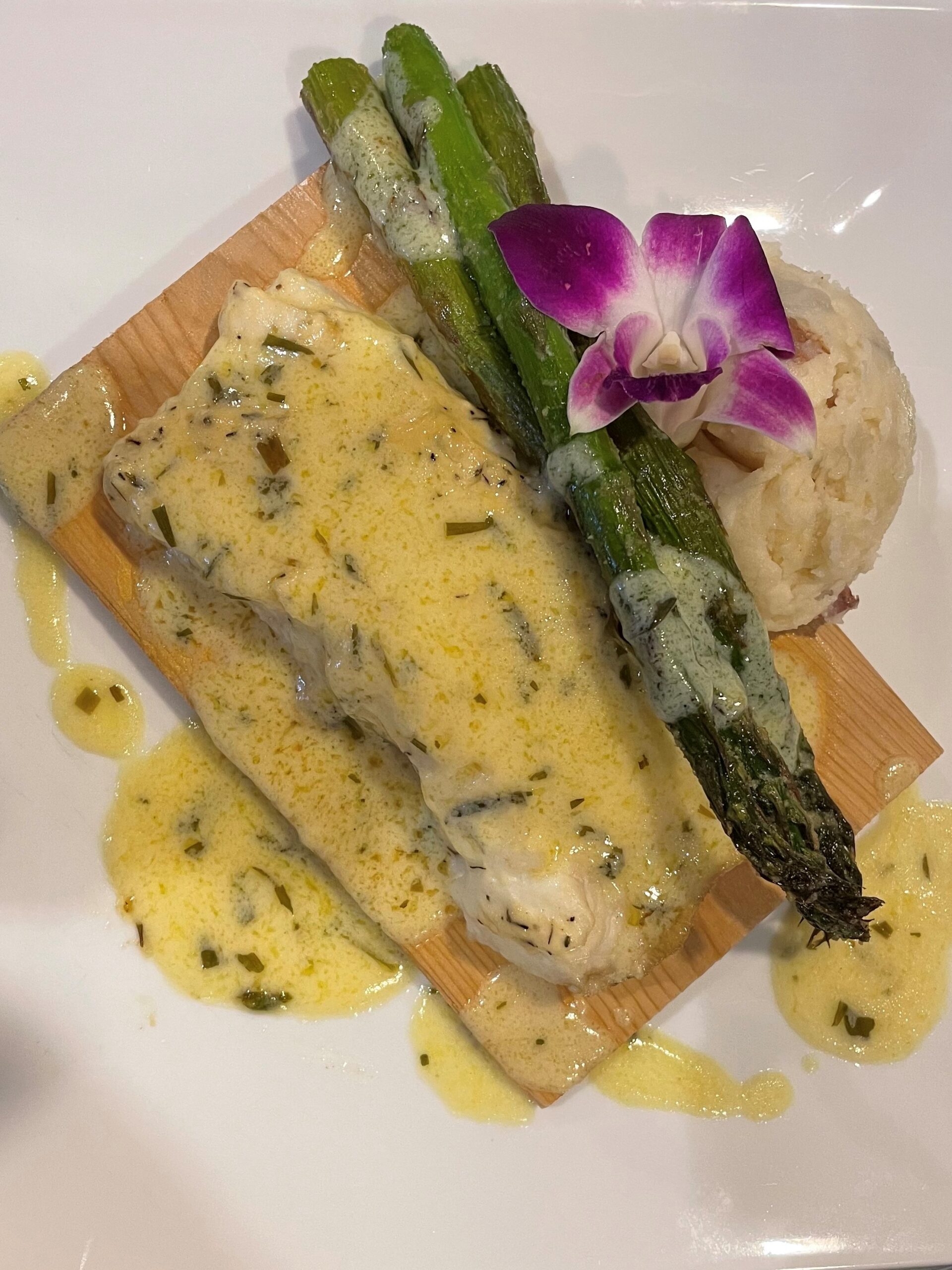 Close-up view of fish with a sauce and asparagus and mashed potatoes on the side