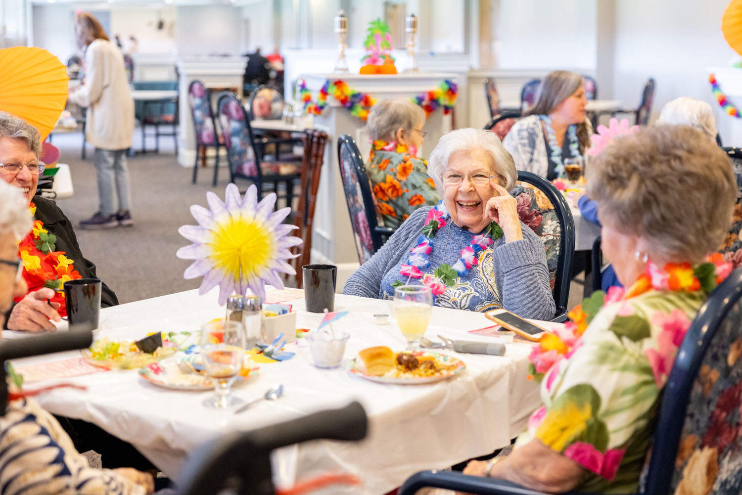 A Day in the Life at Western Reserve Masonic Community - senior women laughing and wearing Hawaiian leis
