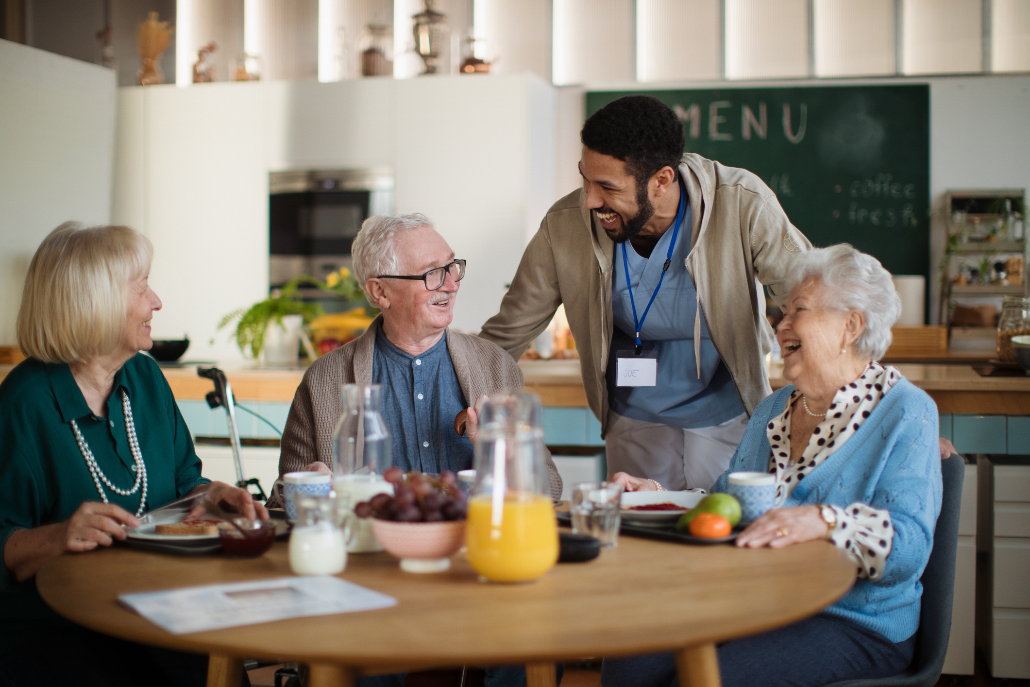 Medical professional talks to three older adults as they dine in a restaurant