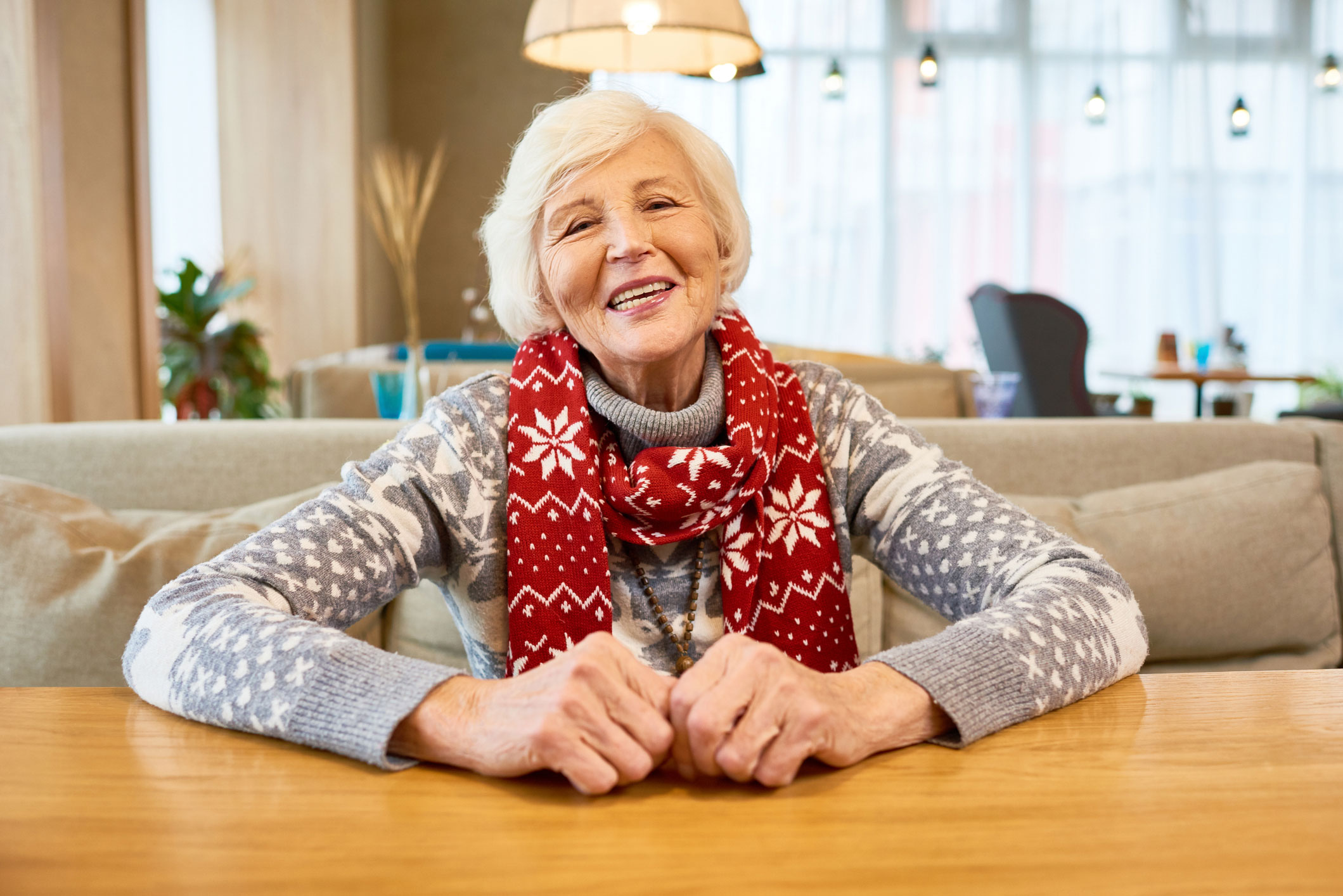 Older adult female wearing sweater and scarf indoors