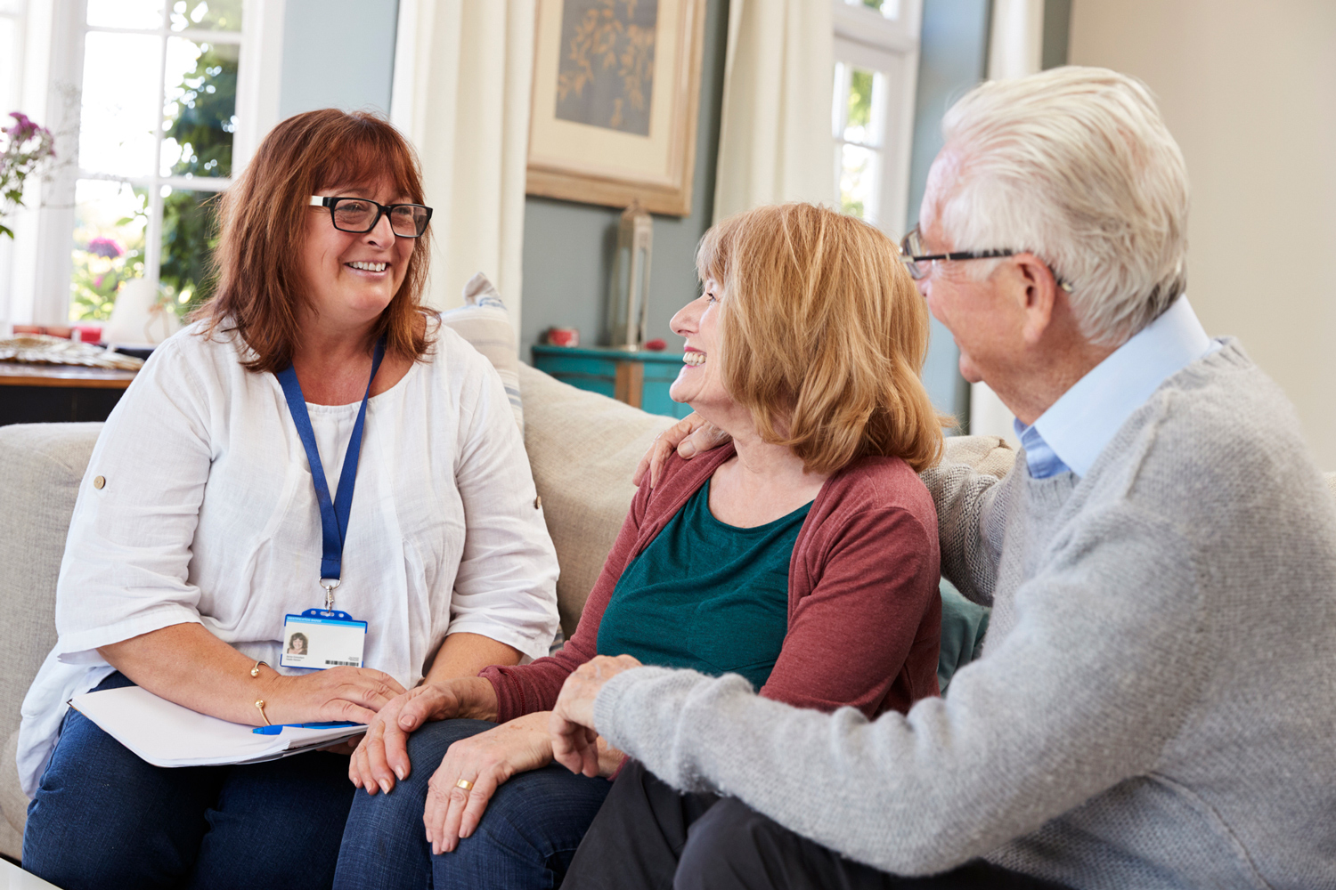 Staff member speaks with older adult couple on a couch