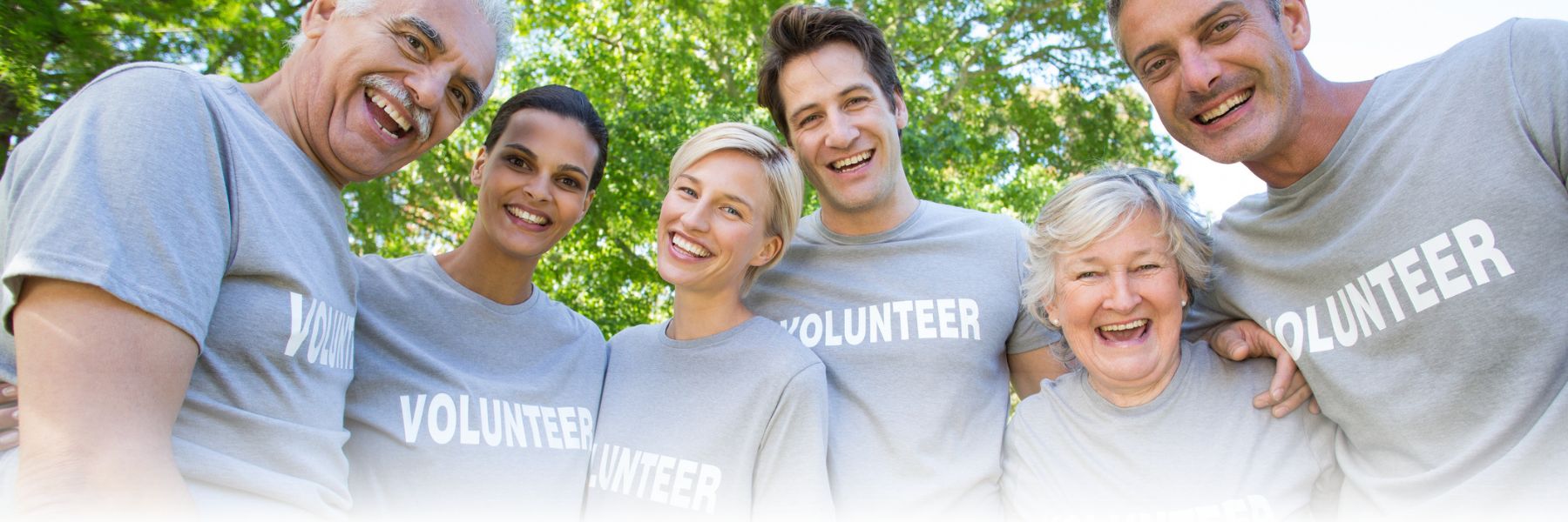 Adults wearing volunteer shirts pose together and smile