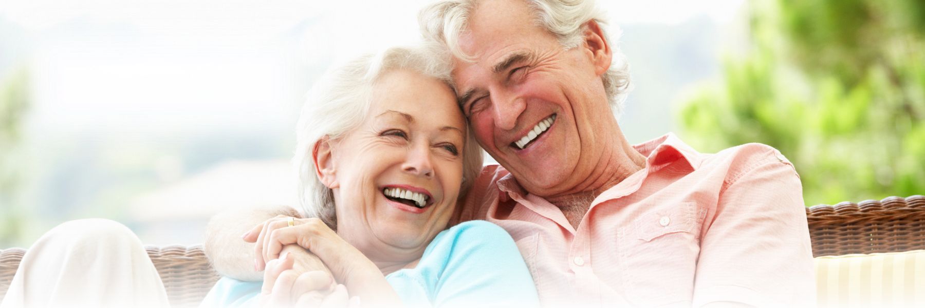 Older adult couple smiles and snuggles outdoors
