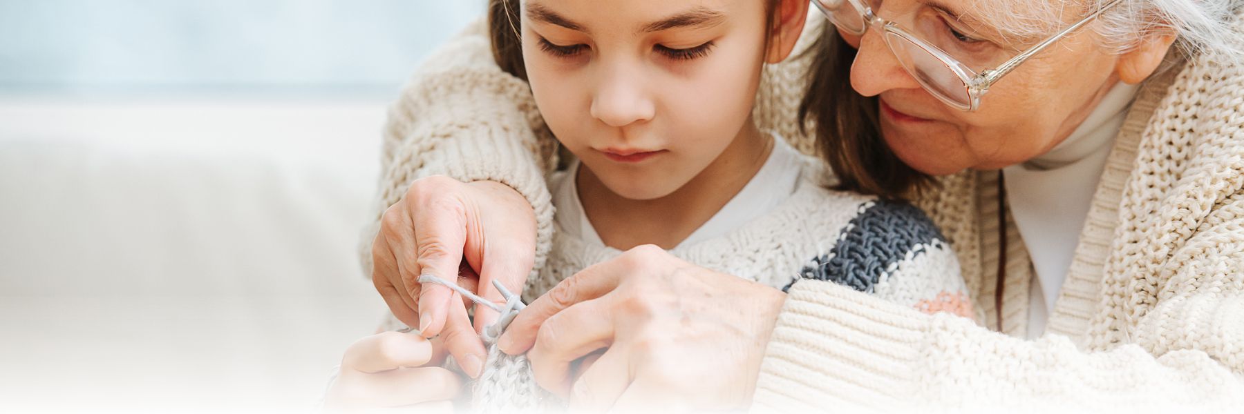 Older adult woman and young girl bonding during the holiday season while knitting