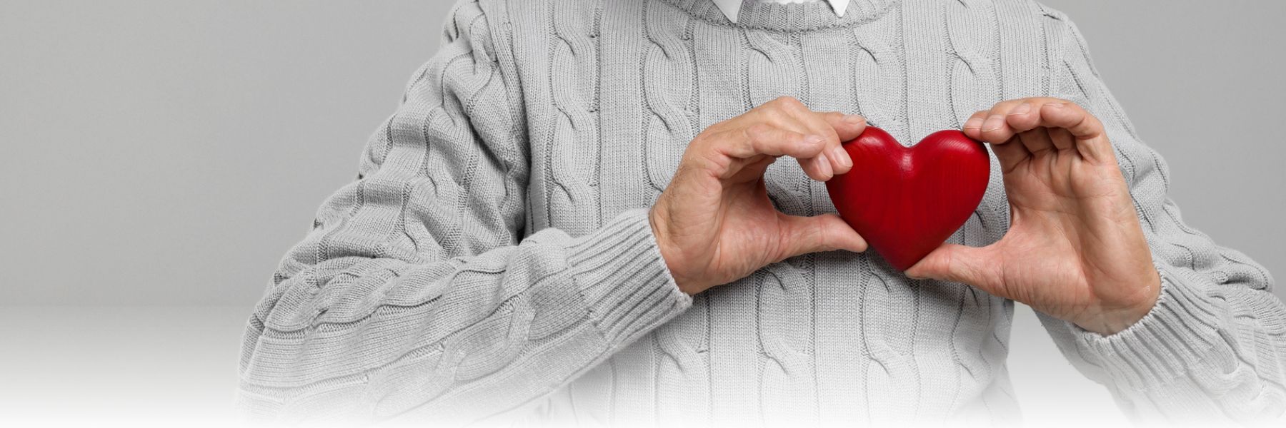 Someone holds a red wooden heart close to their chest