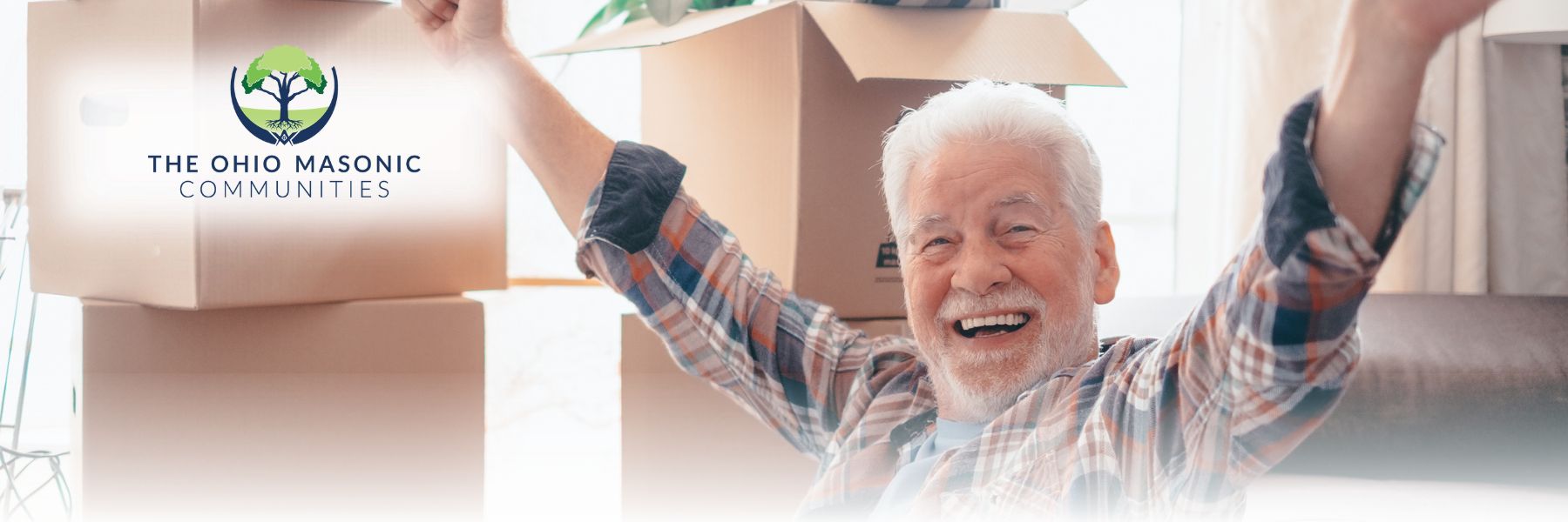 Older adult male smiles with his hands in the air near stacks of boxes