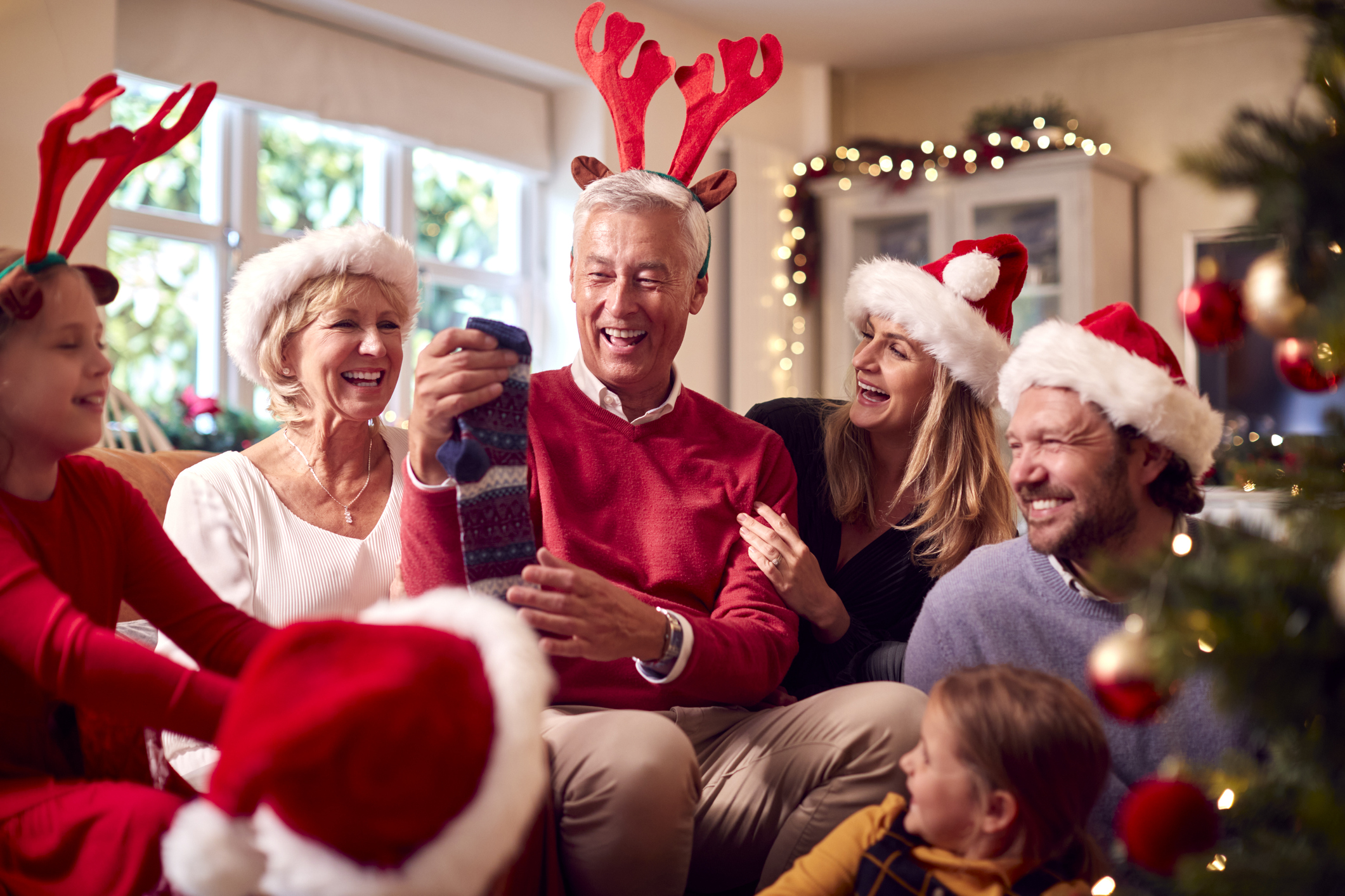 Multi-generation family exchanging and opening gifts around Christmas tree at home