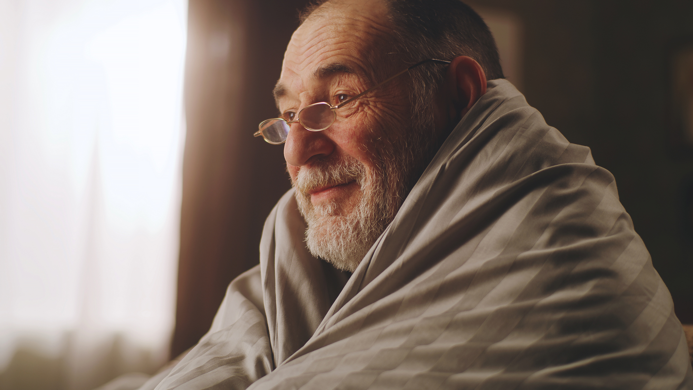 Calm senior man in blanket watching tv