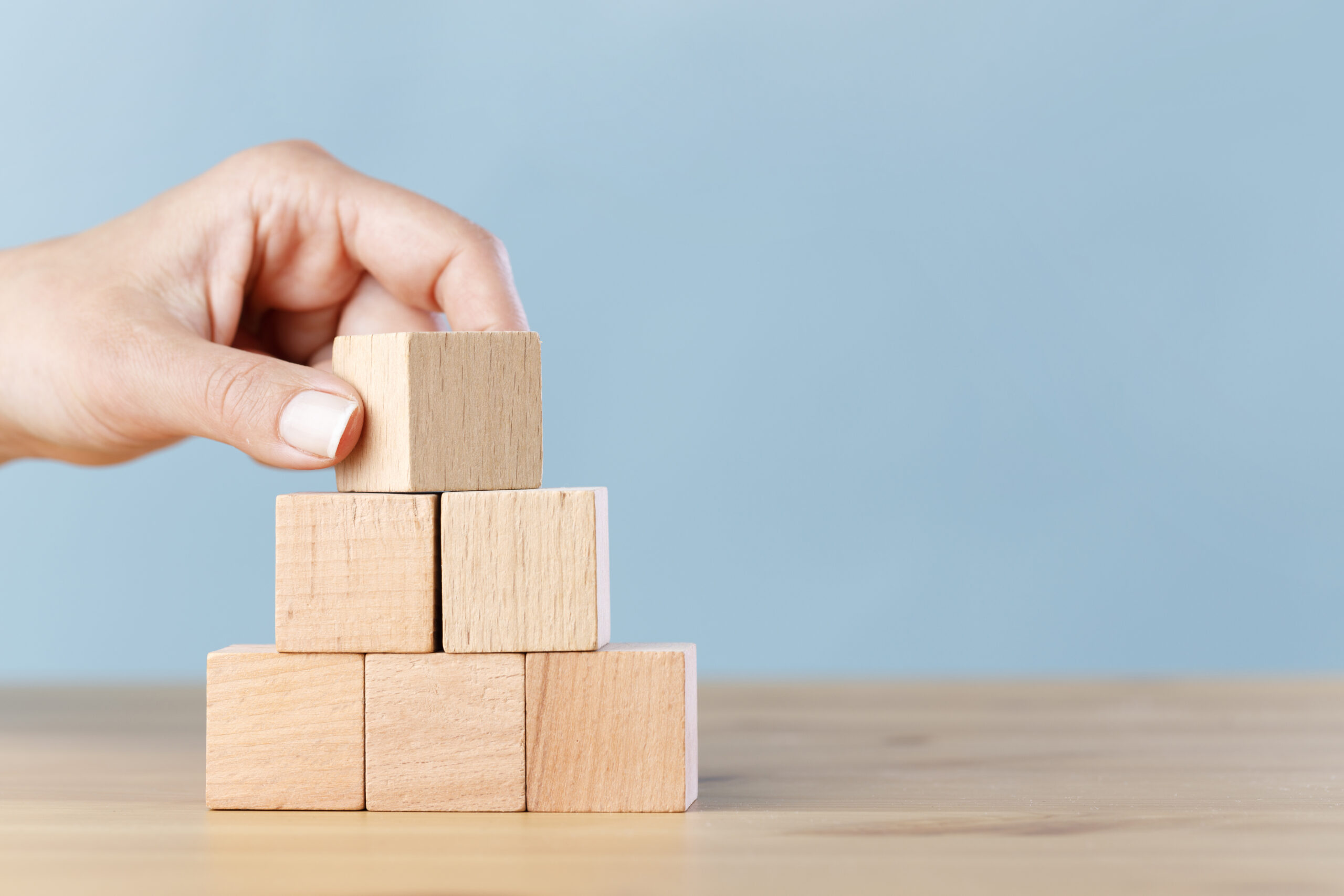 Hand flips blank wooden cube on top pyramid