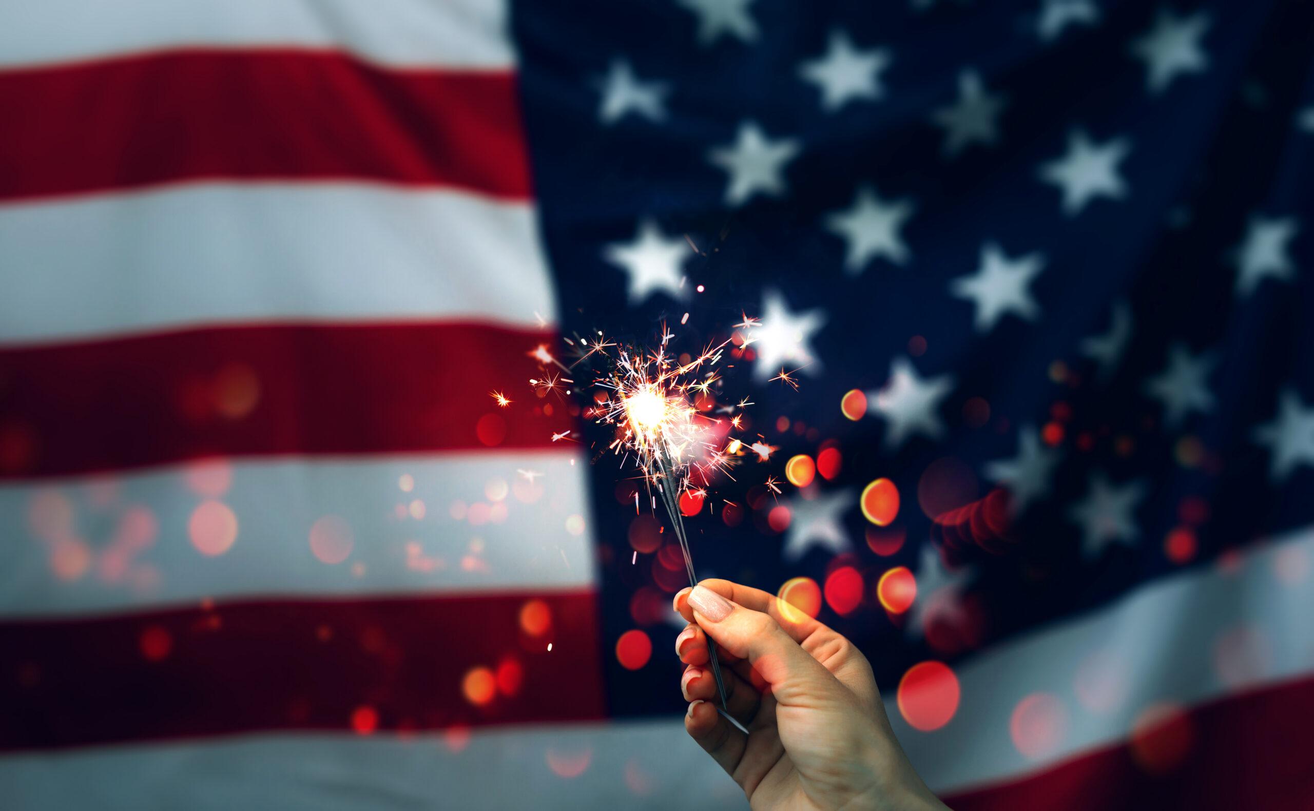 Sparklers in hand on an American Flag background.