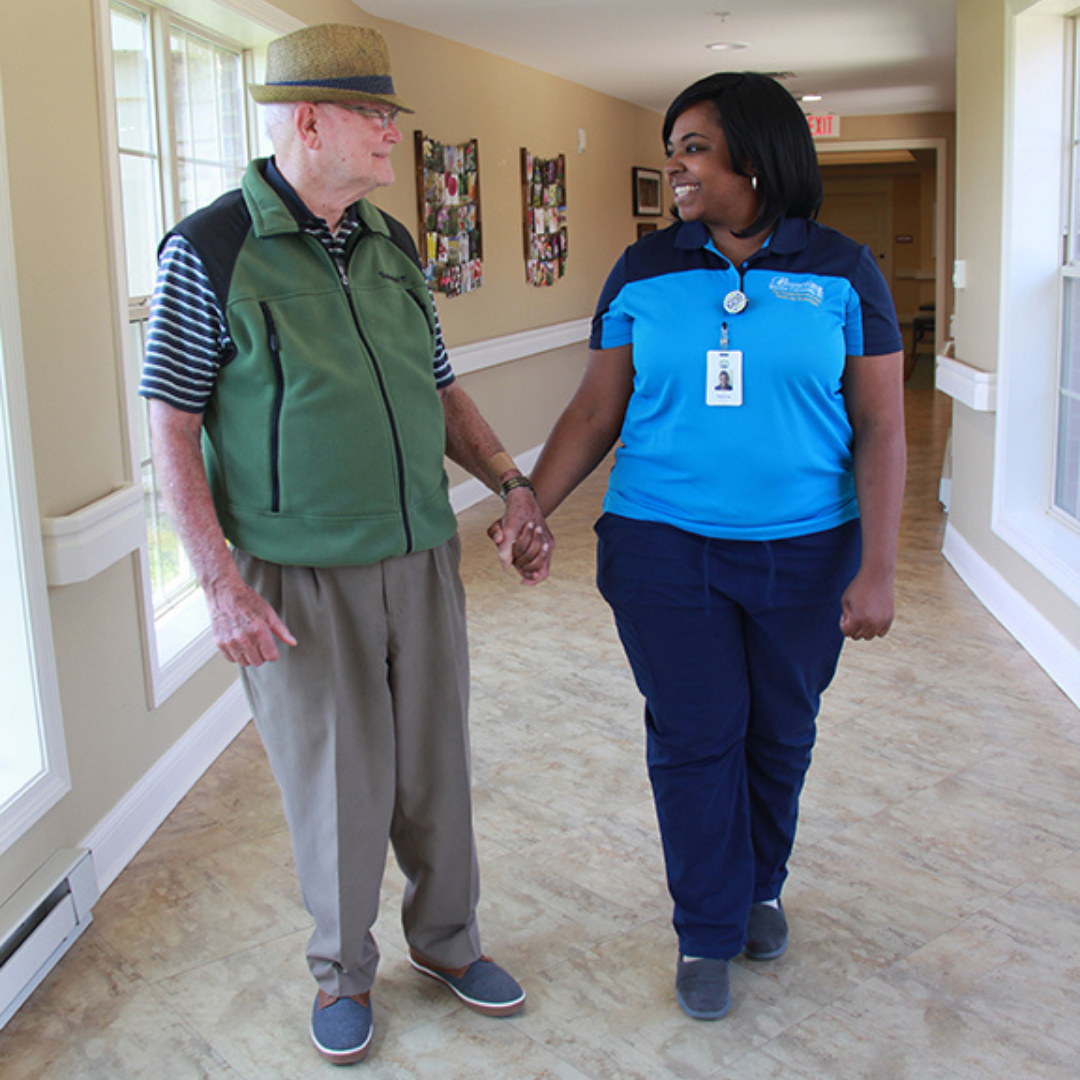 Resident walks hand-in-hand with team member down the hall