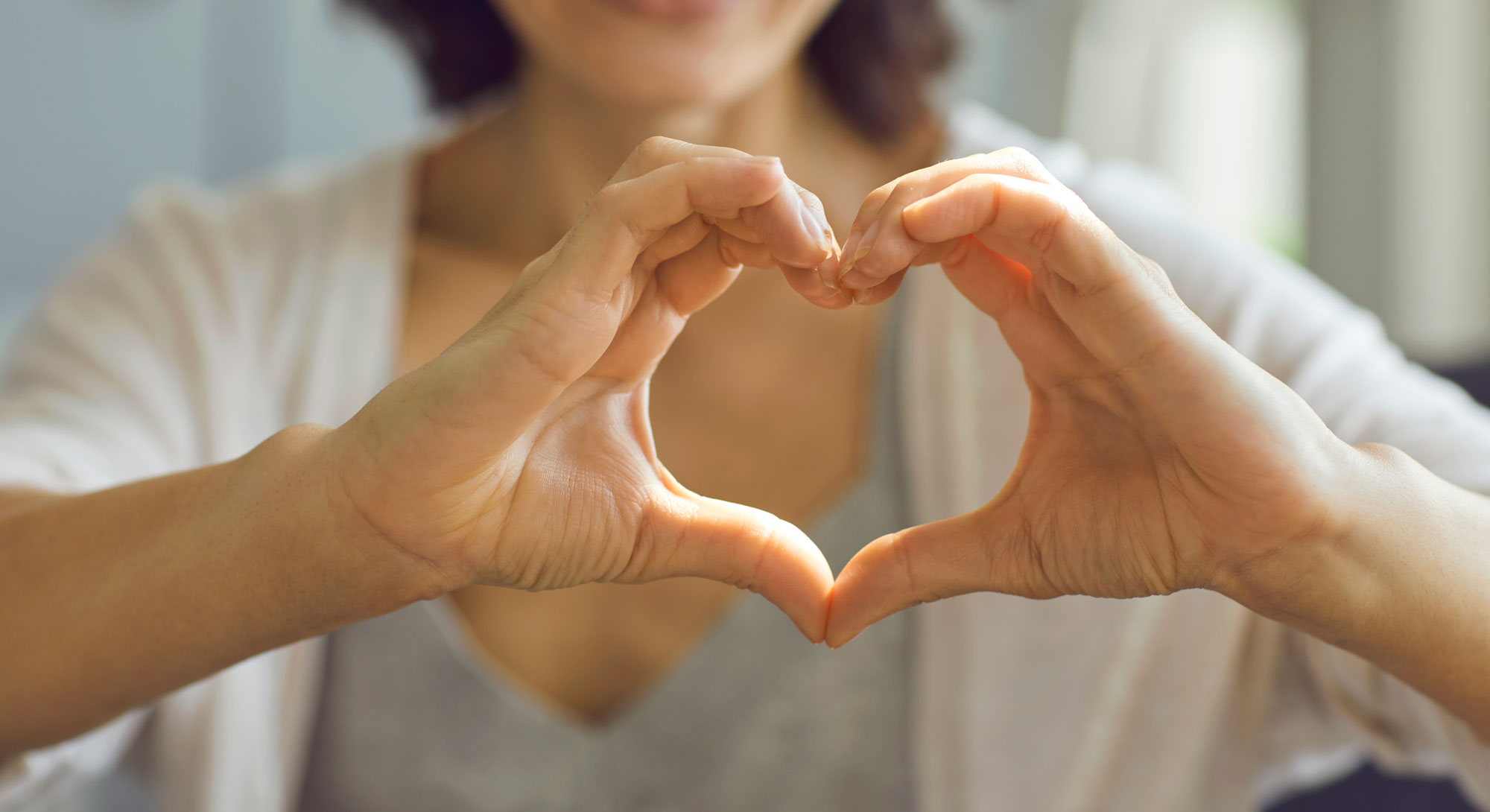 Female holds her hands in the shape of a heart