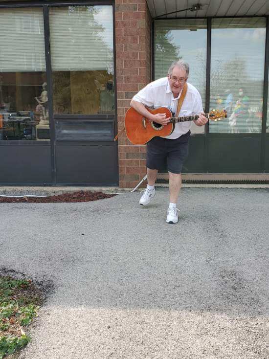 Older adult male playing the guitar outside