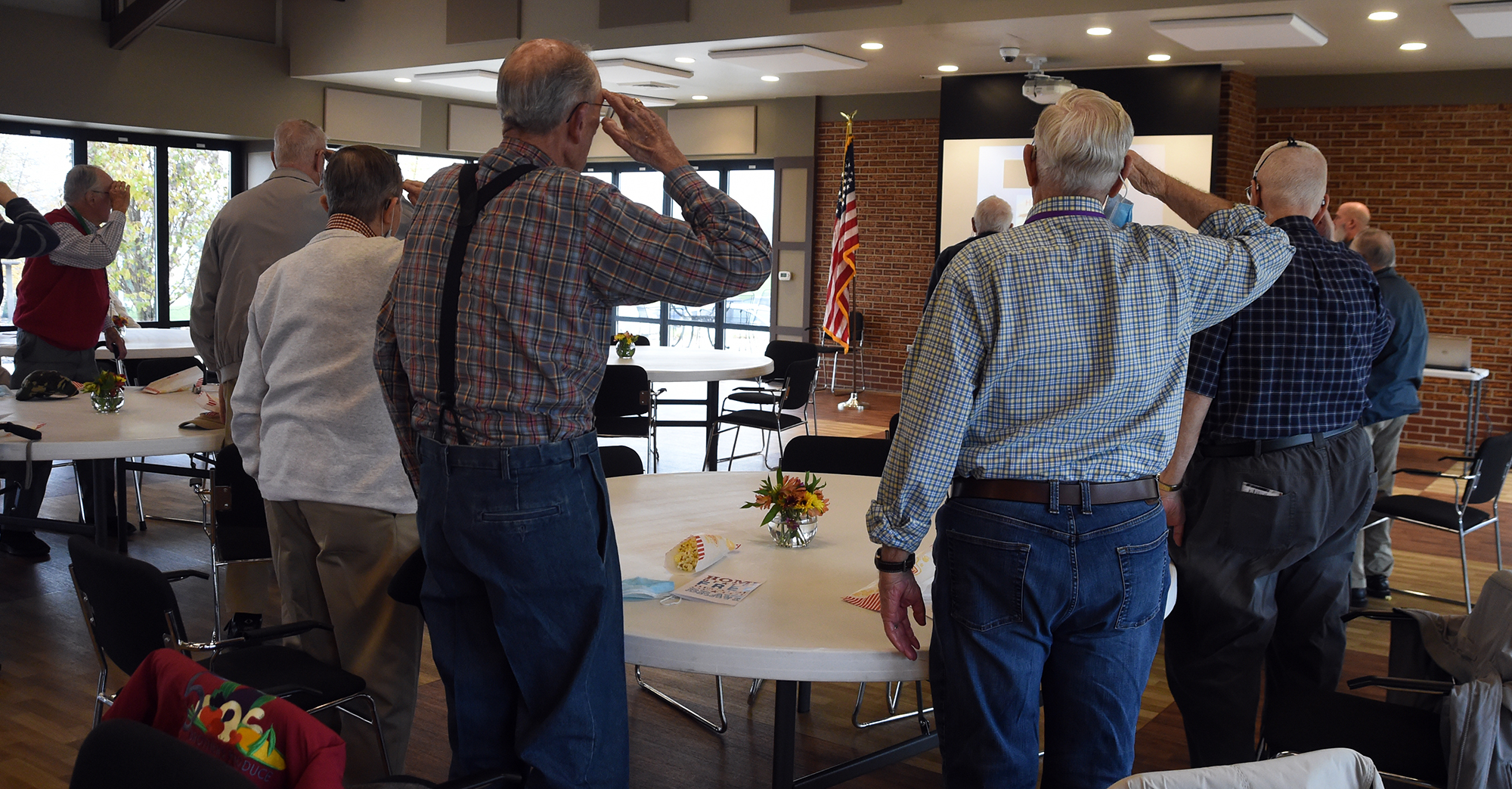 View of residents standing and saluting at the Veterans Day program