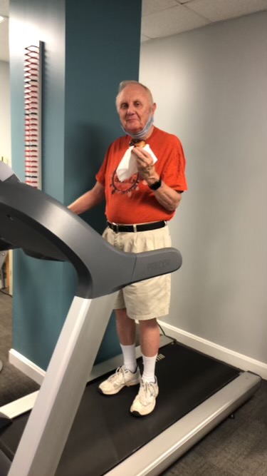 Resident eating a donut while walking on a treadmill